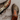 A pair of trail running shoes shown on a dusty concrete surface, with one shoe lying on its side displaying the dirty outsole and the other standing upright showing the side and lace-up closure. The shoes are gray with bright orange accents.