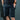 Man wearing the Heat Up heated shorts with hands in pockets, dark background